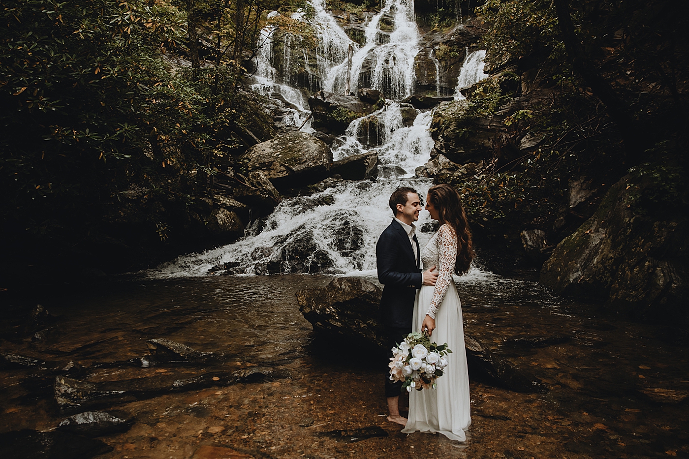 Bride and Groom holding each other in front of rocky water fall Catawba Falls Asheville, NC Elopement Photography captured by Maggie Alvarez Photography