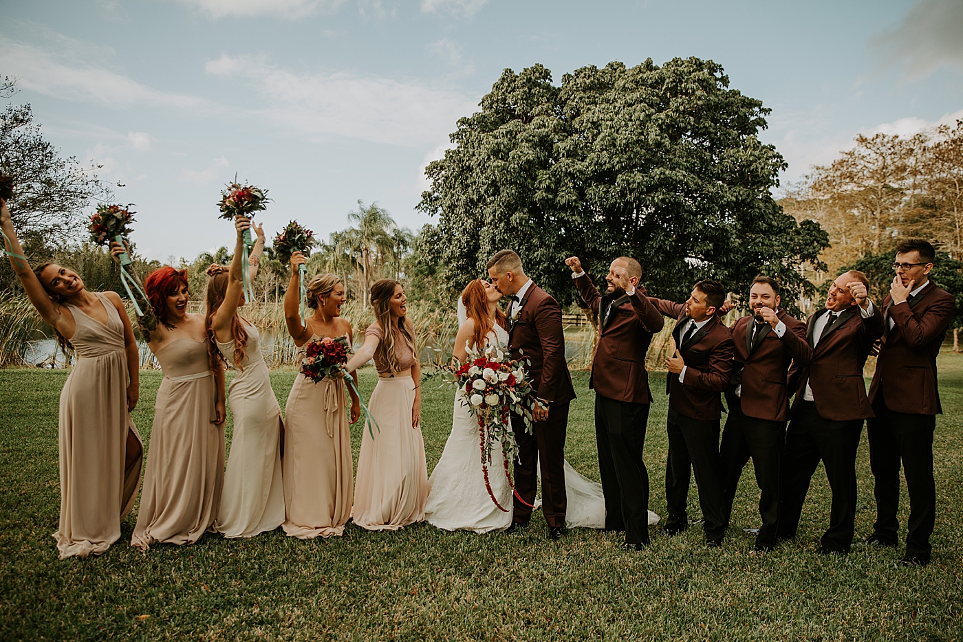 Bride and Groom kiss with celebrating Bridal party Bride entering ceremony with father BMR Stables Wedding Photography captured by South Florida Wedding Photographer Maggie Alvarez Photography