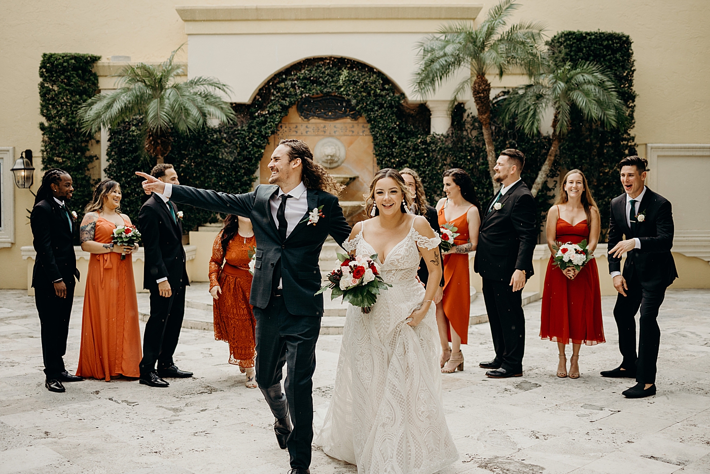 Bride and Groom excitedly walking with Wedding party behind Benvenuto Restaurant Wedding Photography captured by South Florida Wedding Photographer Maggie Alvarez Photography