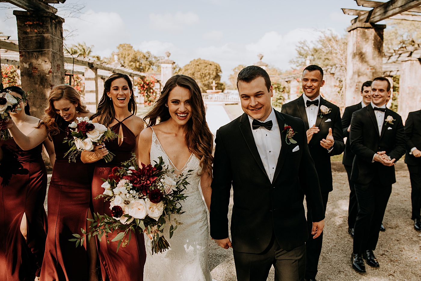 Bride and Groom holding hands with Bridal Party following from behind Coral Gables Country Club Wedding Photography captured by South Florida Wedding Photographer Maggie Alvarez Photography