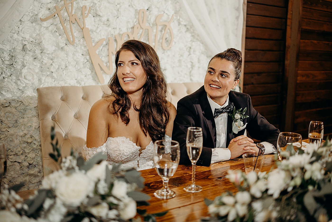 Brides sitting at white floral sweetheart table Ever After Farms Wedding Photography captured by South Florida Wedding Photographer Maggie Alvarez Photography