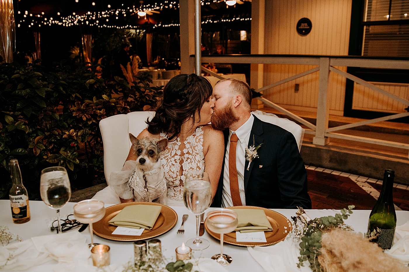 Bride and Groom kissing at sweetheart table with dog Historic Stranahan House Wedding Photography captured by South Florida Wedding Photographer Maggie Alvarez Photography