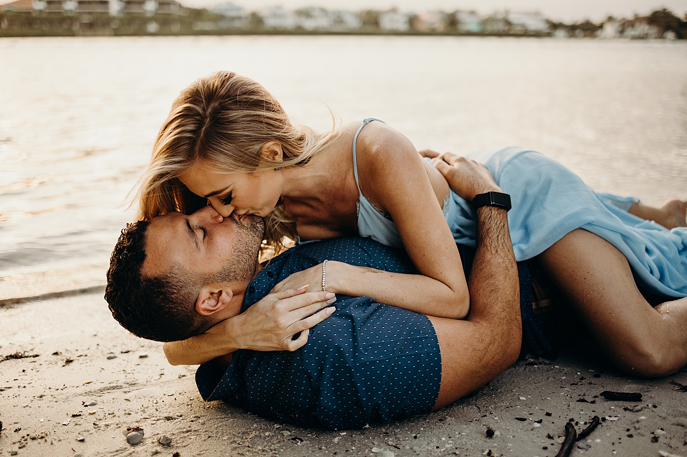 Man laying on beach and kissing woman on top Coral Cove Park Engagement Photography captured by Maggie Alvarez Photography
