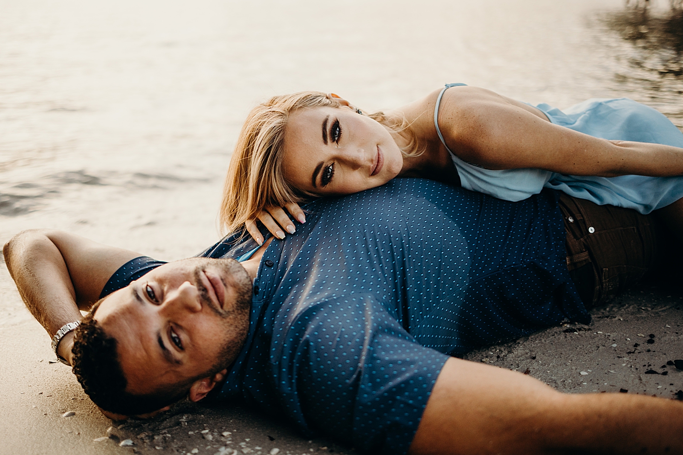Man laying on beach and lady on top Coral Cove Park Engagement Photography captured by Maggie Alvarez Photography