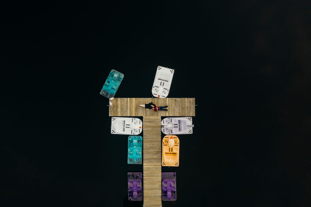 Drone photo of a couple laying on a dock at Tree Top Park Engagement Photography captured by Maggie Alvarez Photography