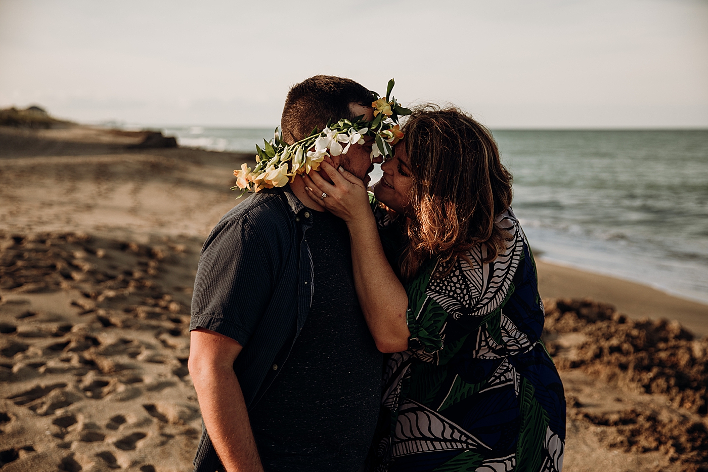 Couple kissing on the beach with man wearing floral crown House of Refuge Engagement Photography captured by Maggie Alvarez Photography