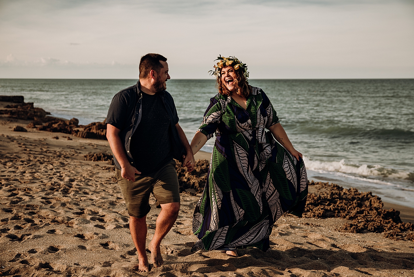 Couple holding hands laughing and strolling on the beach House of Refuge Engagement Photography captured by Maggie Alvarez Photography