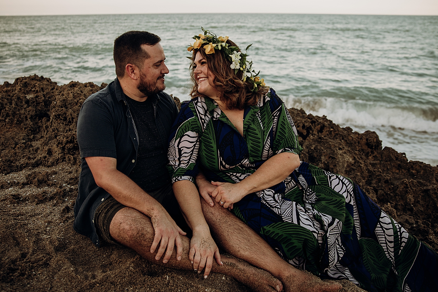 Couple sitting on rock and holding each other looking at each other House of Refuge Engagement Photography captured by Maggie Alvarez Photography