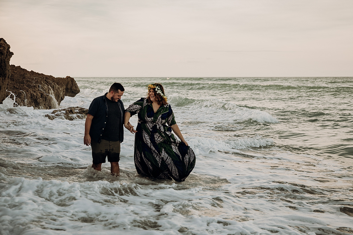 Couple walking through the ocean holding hands House of Refuge Engagement Photography captured by Maggie Alvarez Photography