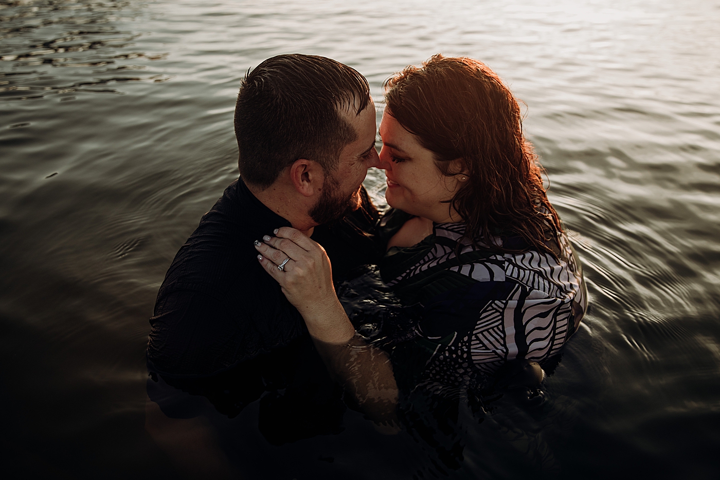 Couple nuzzling and holding each other in calm ocean water House of Refuge Engagement Photography captured by Maggie Alvarez Photography