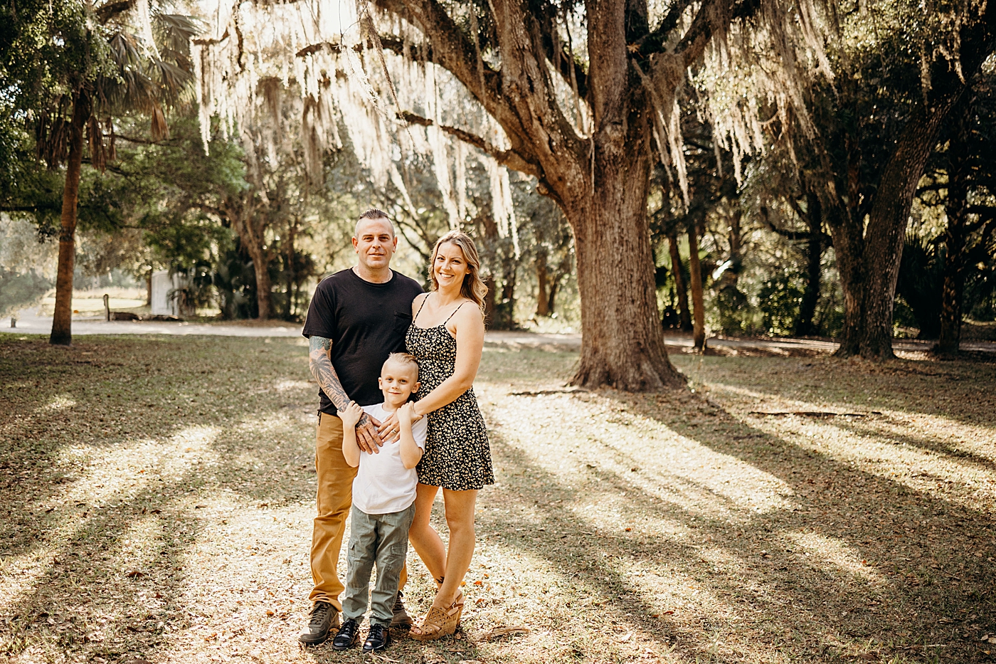Family portrait of parents with there hands on child with spanish moss tree behind them Riverbend Park Family Photography by South Florida Family Photographer Maggie Alvarez Photography