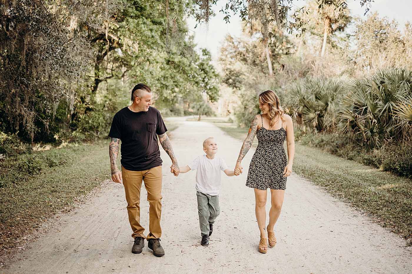 Parents holding child's hands and walking down park natural path Riverbend Park Family Photography by South Florida Family Photographer Maggie Alvarez Photography