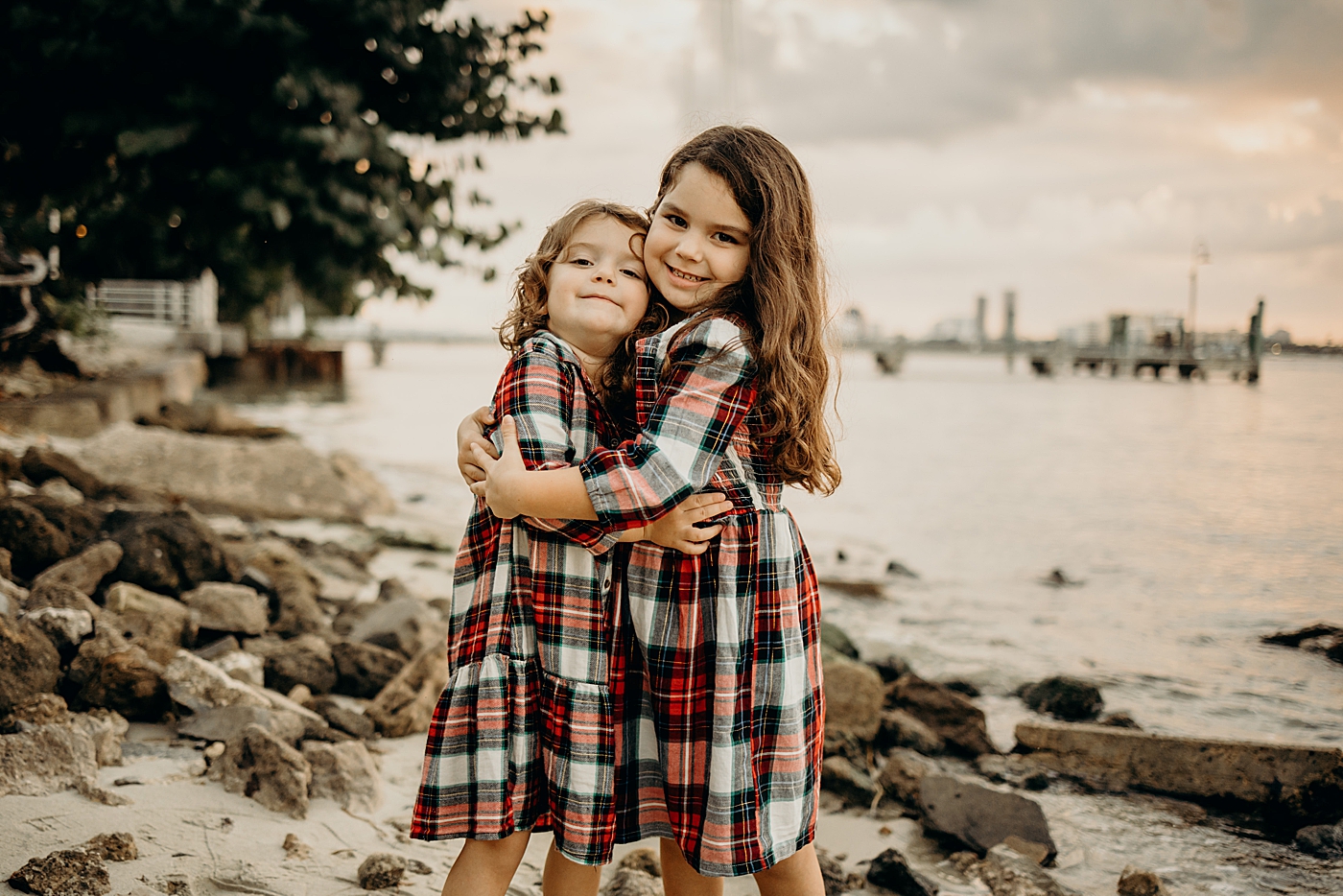 Siblings hugging each other on rocky beach Palm Beach Island Family Photography by South Florida Family Photographer Maggie Alvarez Photography