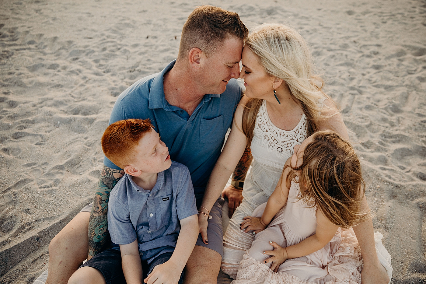 Parents nuzzling with kids in their lap on the beach Ocean Ridge Hammock Park Family Photography by South Florida Family Photographer Maggie Alvarez Photography
