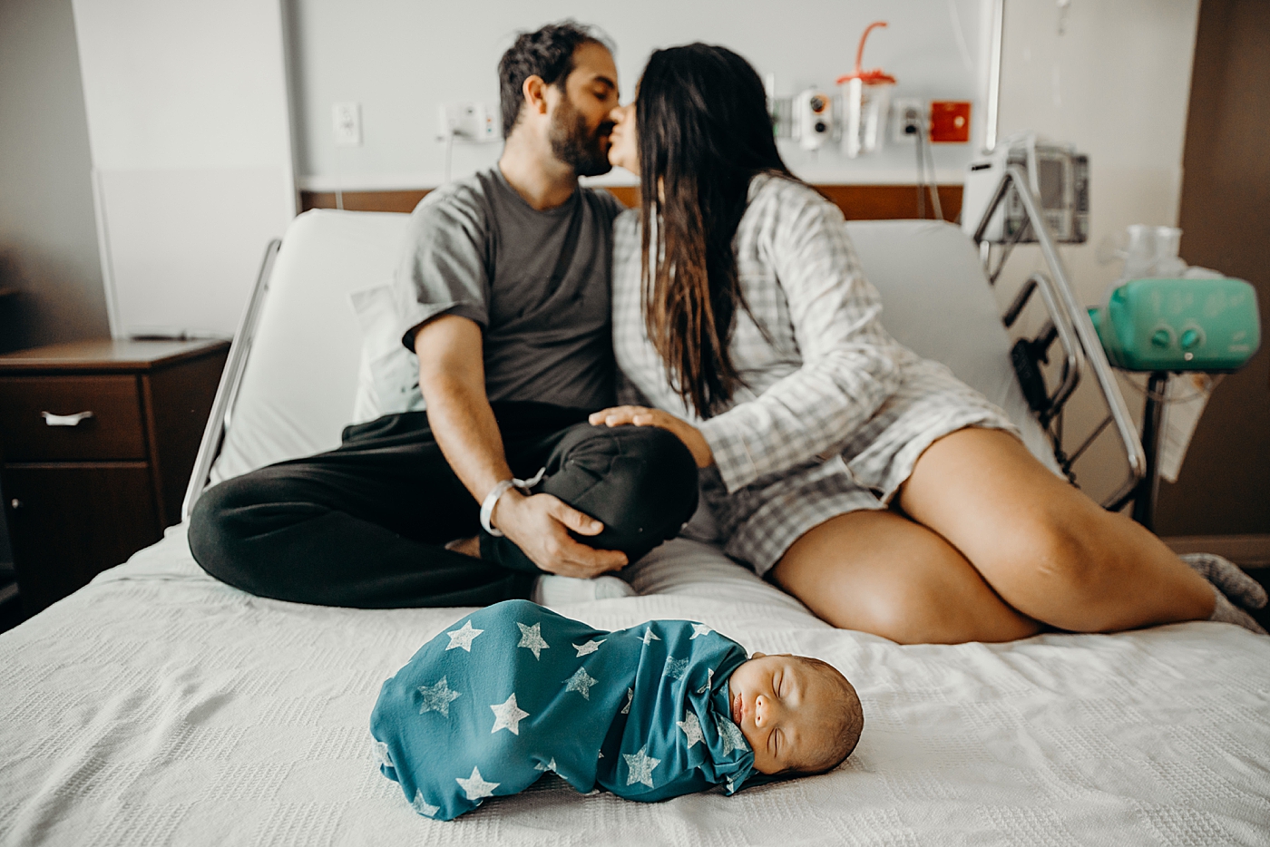 Parents kissing with baby in star swaddle laying down sleeping South Florida Fresh 48 Newborn Photography by South Florida Family Photographer Maggie Alvarez Photography