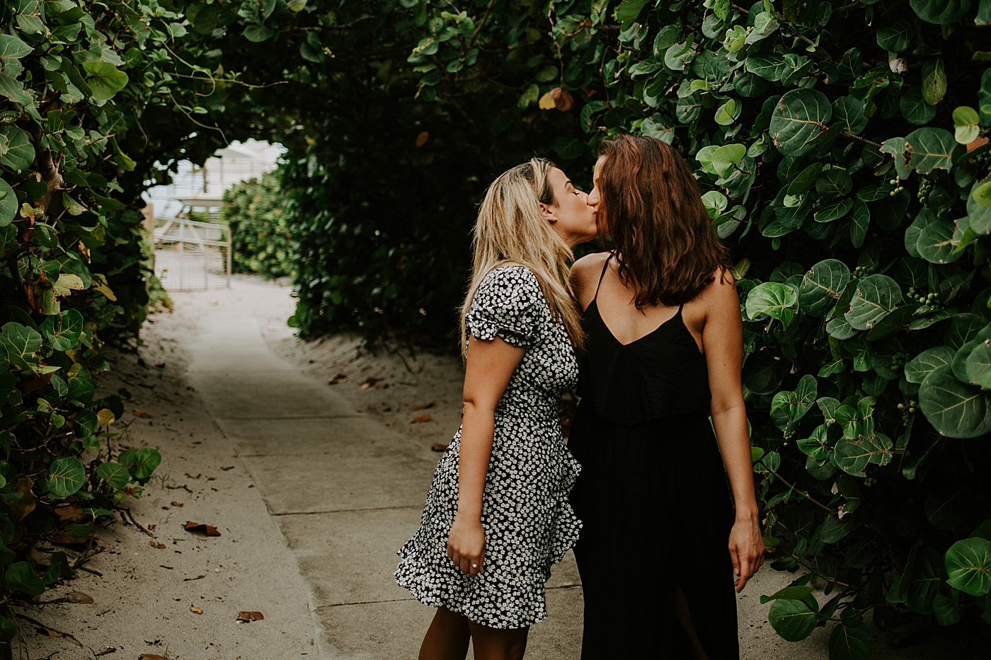 Couple kissing under greenery archway South Florida LGBTQ+ Engagement Photography captured by Maggie Alvarez Photography