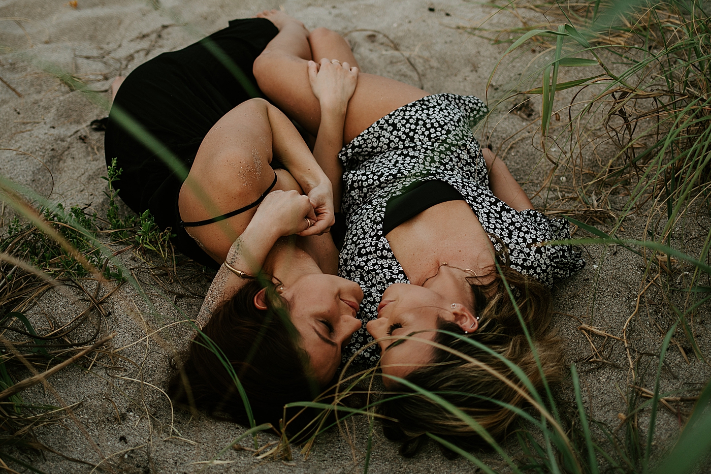 Couple laying down next to each other on the sand South Florida LGBTQ+ Engagement Photography captured by Maggie Alvarez Photography