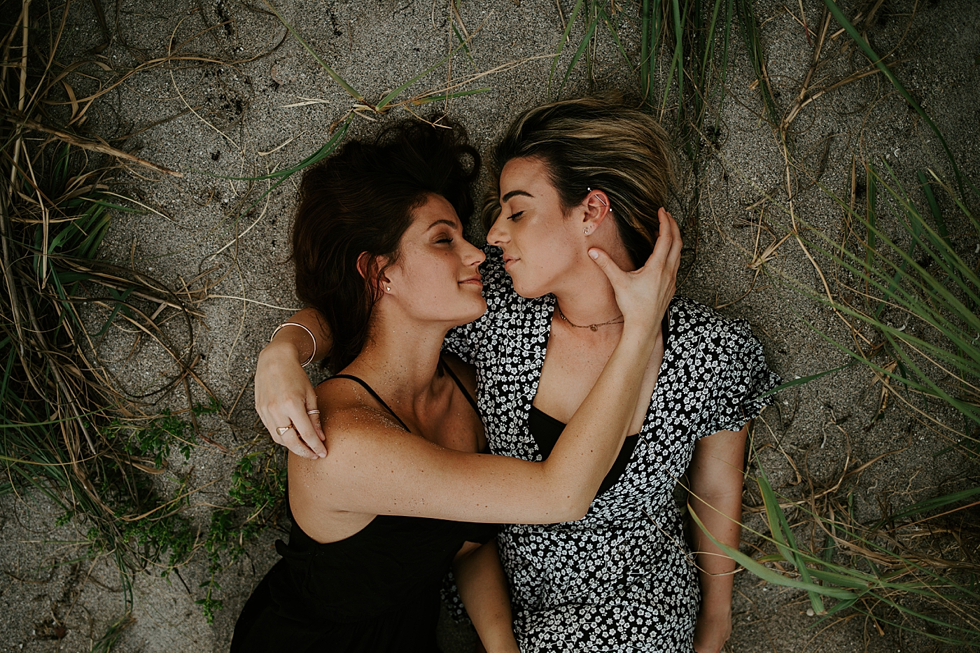 Couple laying on sand holding each other South Florida LGBTQ+ Engagement Photography captured by Maggie Alvarez Photography