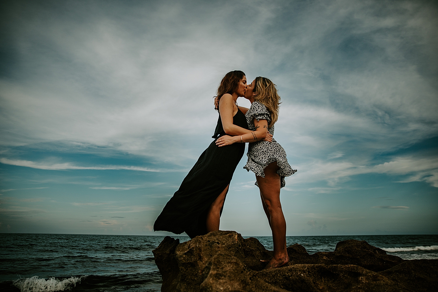 Couple kissing on rock with ocean behind them South Florida LGBTQ+ Engagement Photography captured by Maggie Alvarez Photography