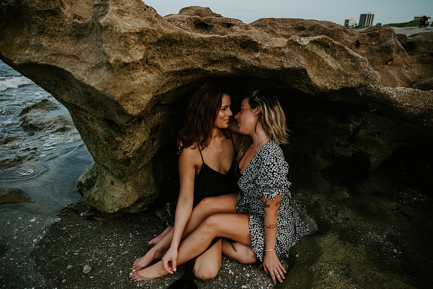 Couple under beach rock and in the beach water South Florida LGBTQ+ Engagement Photography captured by Maggie Alvarez Photography