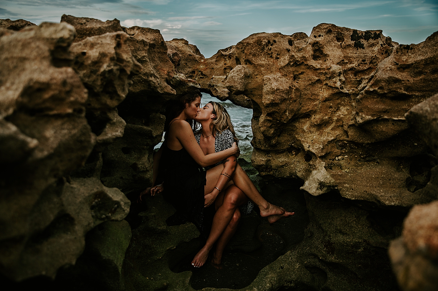Couple sitting on rock and kissing South Florida LGBTQ+ Engagement Photography captured by Maggie Alvarez Photography