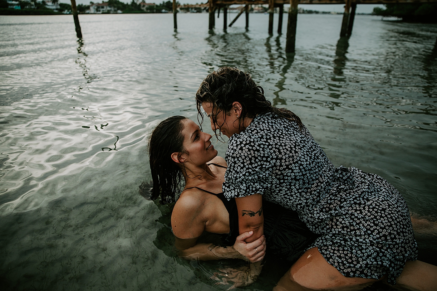 Woman on top of lady looking at each other in the water South Florida LGBTQ+ Engagement Photography captured by Maggie Alvarez Photography