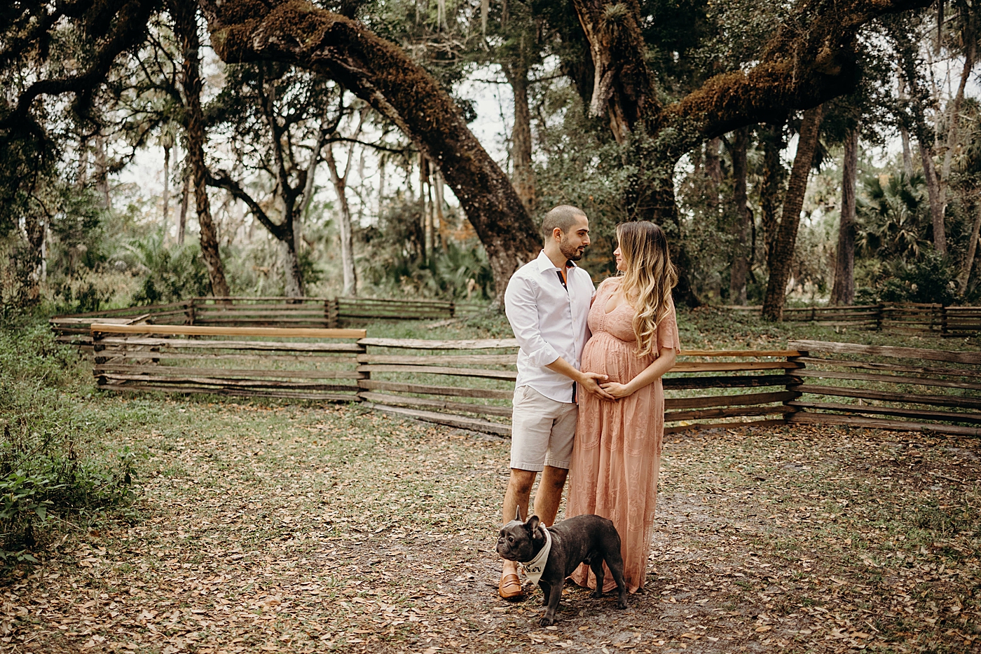 Couple looking at each other with dog by their feet Riverbend Park Maternity Photography by South Florida Family Photographer Maggie Alvarez Photography