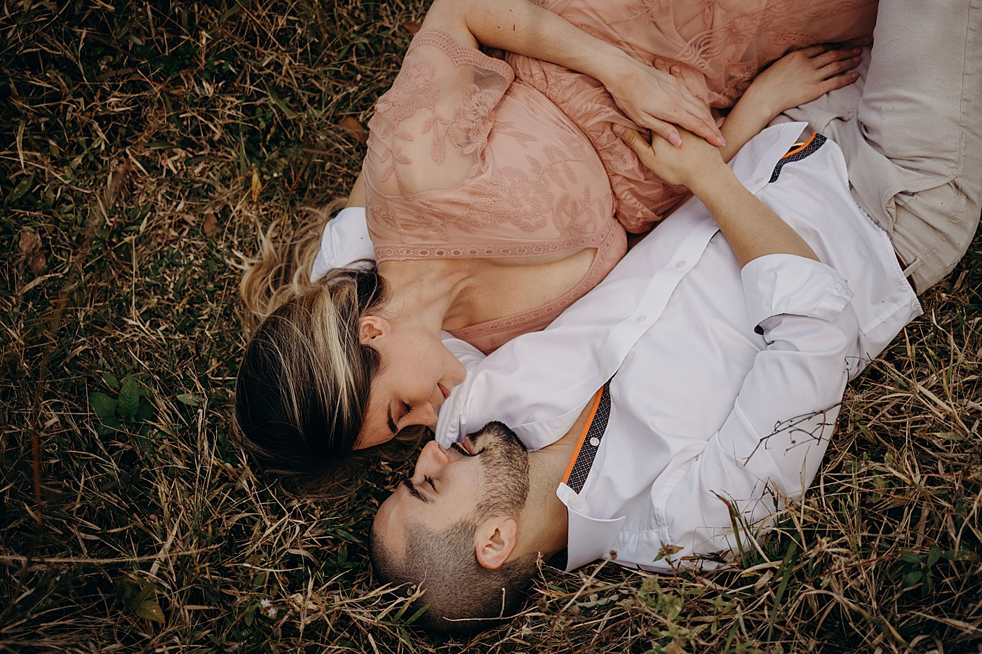 Couple laying down in grassy field with heads turned to each other Riverbend Park Maternity Photography by South Florida Family Photographer Maggie Alvarez Photography