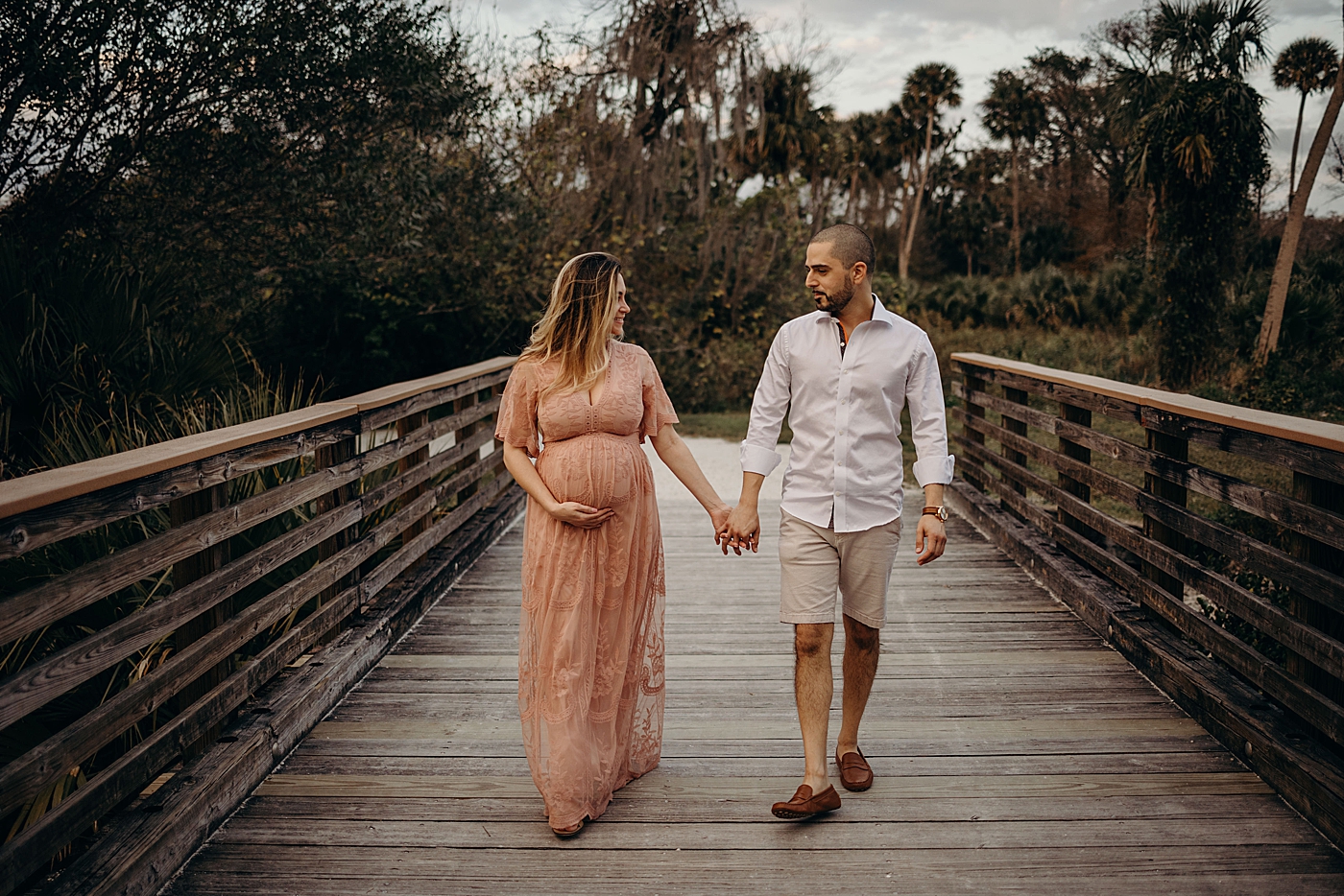 Couple holding hands as they walk across bridge Riverbend Park Maternity Photography by South Florida Family Photographer Maggie Alvarez Photography