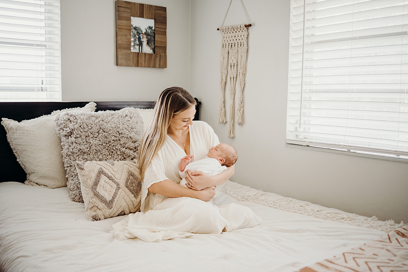 Mother cradling baby in arms on the bed South Florida Newborn Photography captured by South Florida Family Photographer Maggie Alvarez Photography