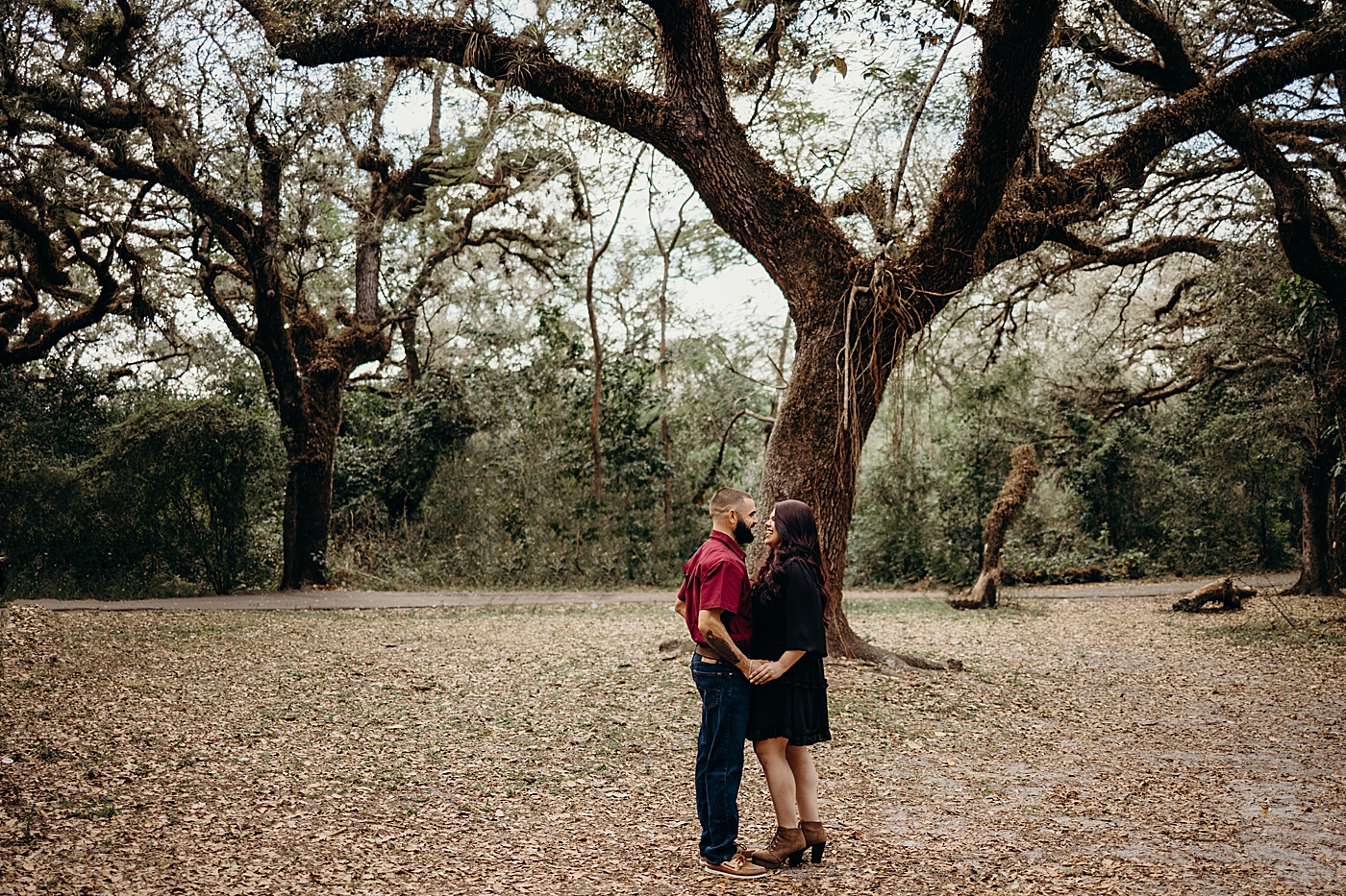 Couple holding each other with fall leafs and trees Tree Top Park Engagement Photography captured by Maggie Alvarez Photography