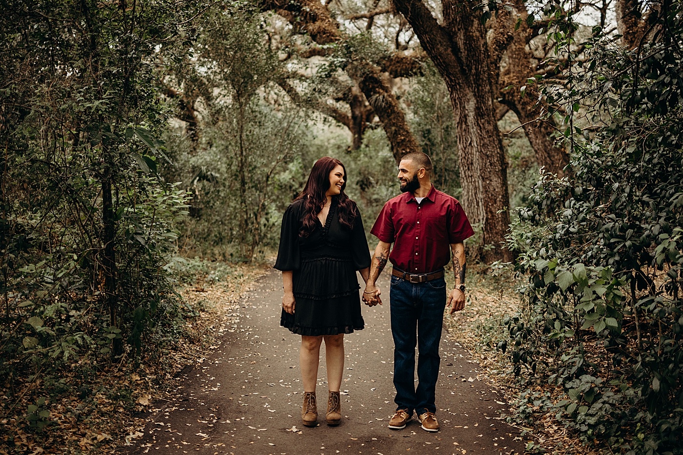 Couple holding hands on sidewalk in the park Tree Top Park Engagement Photography captured by Maggie Alvarez Photography