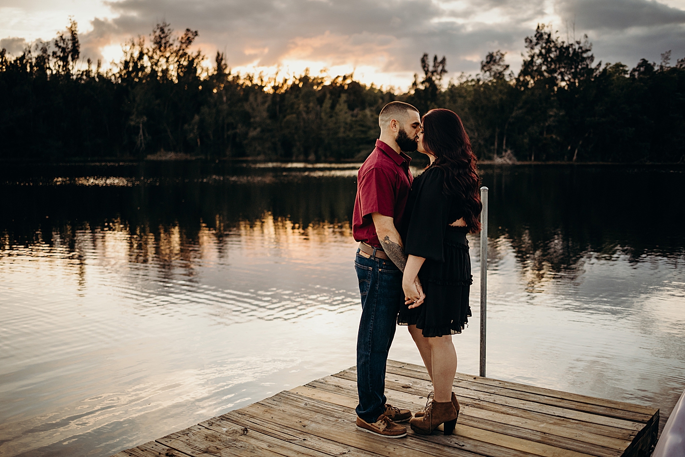 Couple kissing on dock by calm water Tree Top Park Engagement Photography captured by Maggie Alvarez Photography
