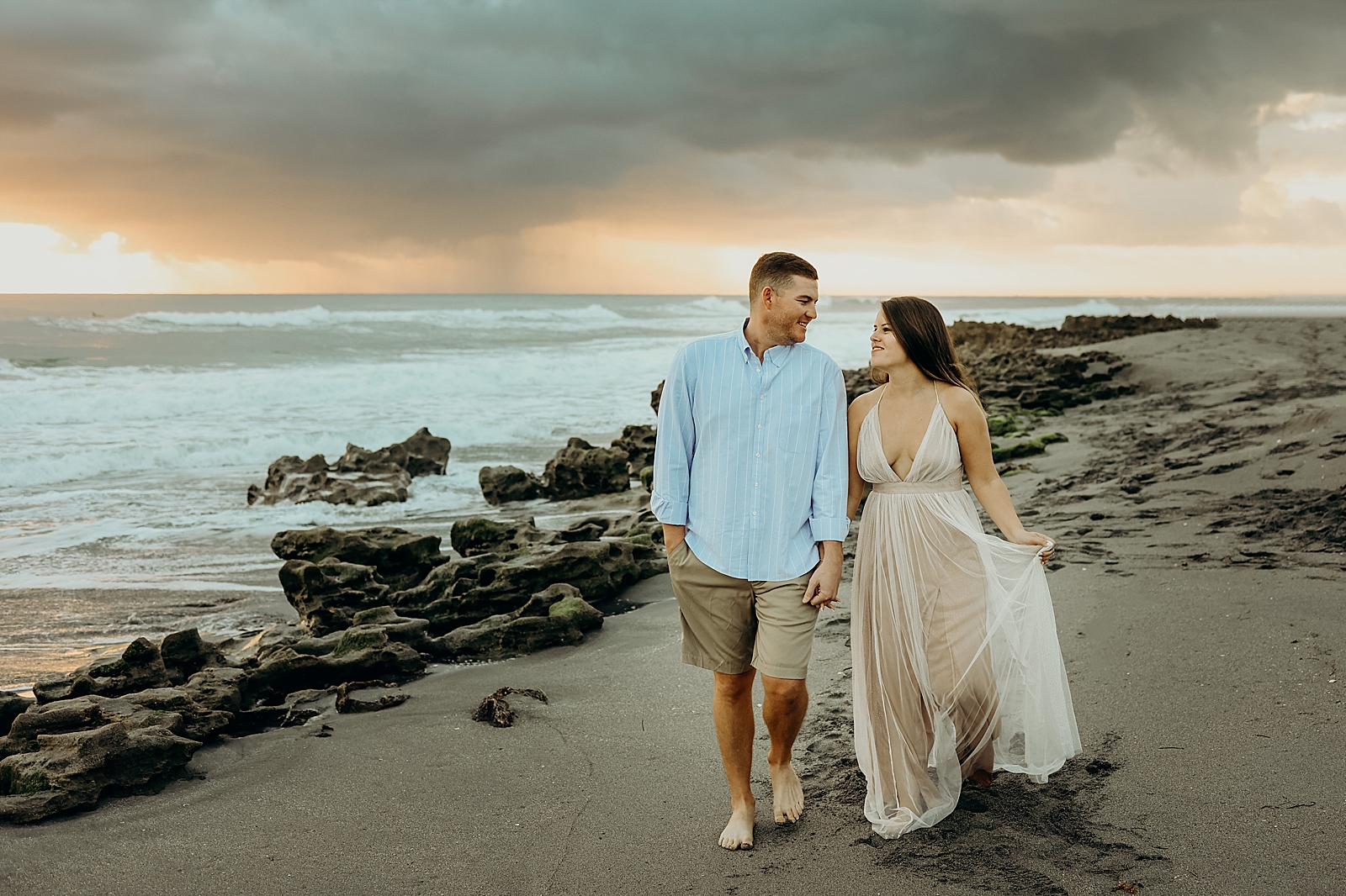 Couple holding hands and strolling on the sand Coral Cove Park Engagement Photography captured by South Florida Family Photographer Maggie Alvarez Photography