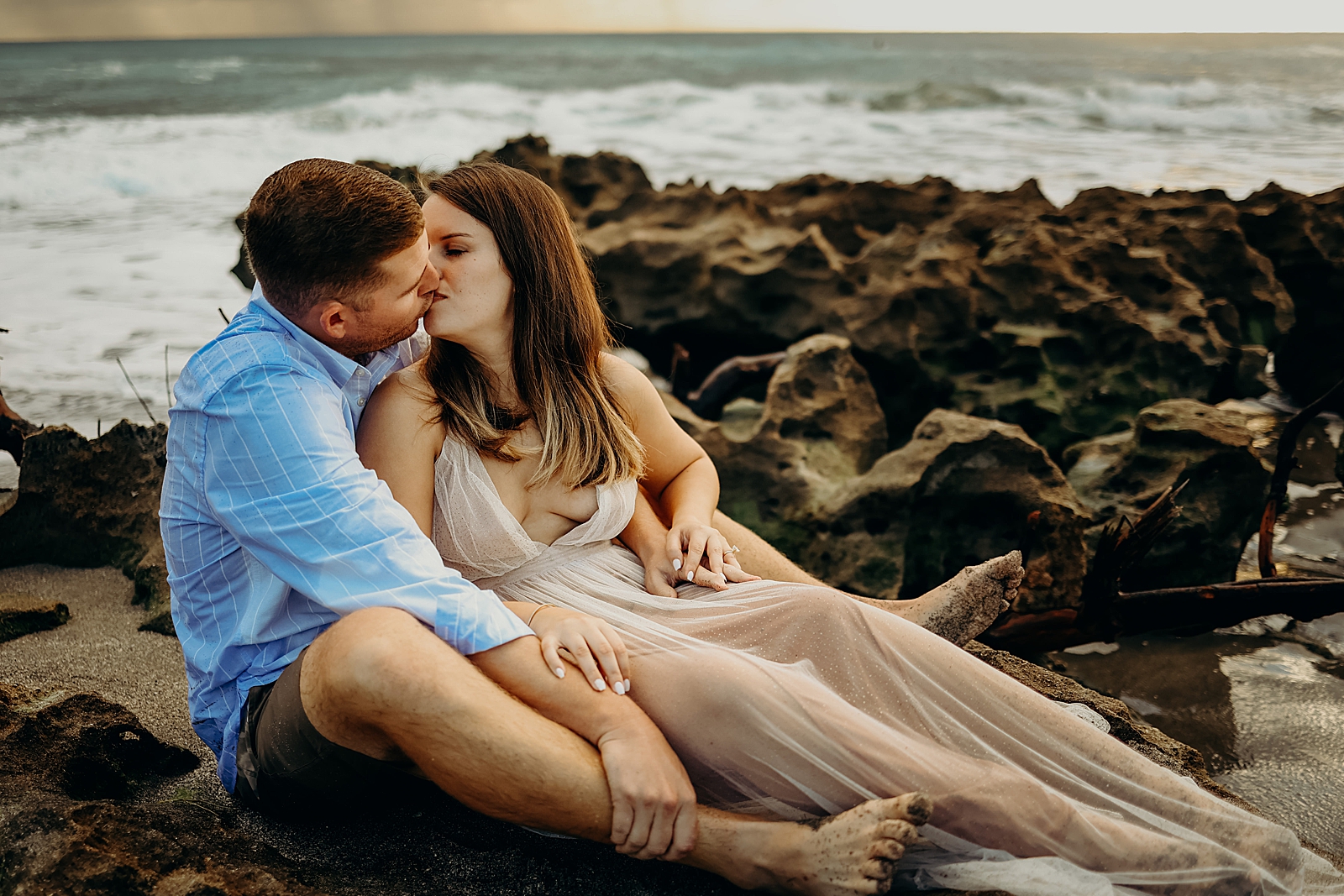 Couple kissing sitting on the beach Coral Cove Park Engagement Photography captured by South Florida Family Photographer Maggie Alvarez Photography