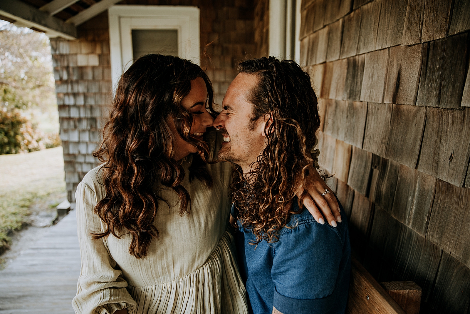 Couple touching noses while sitting on front porch bench Dubois Park Engagement Photography captured by South Florida Family Photographer Maggie Alvarez Photography