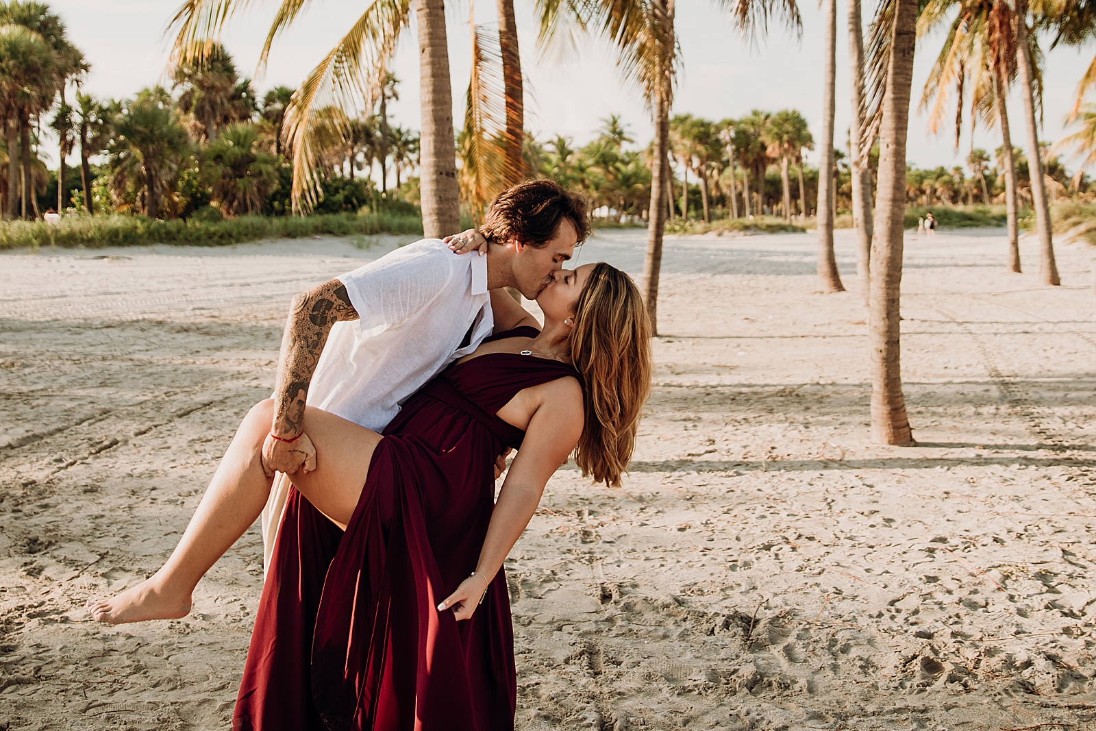 Couple dipping and kissing on sandy ground Key Biscayne Beach Engagement Photography captured by South Florida Family Photographer Maggie Alvarez Photography