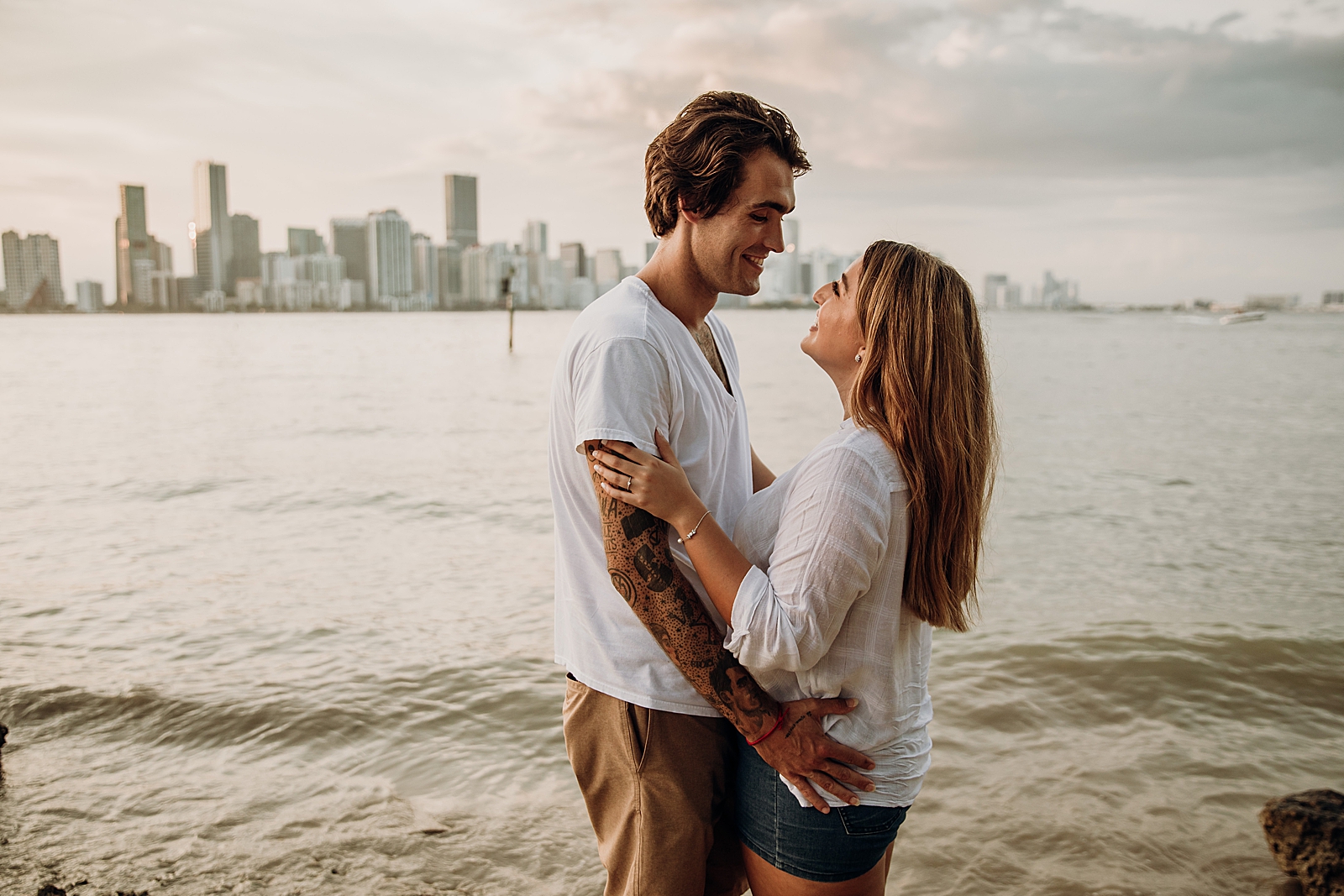 Couple holding and looking at each other in front of the water Key Biscayne Beach Engagement Photography captured by South Florida Family Photographer Maggie Alvarez Photography