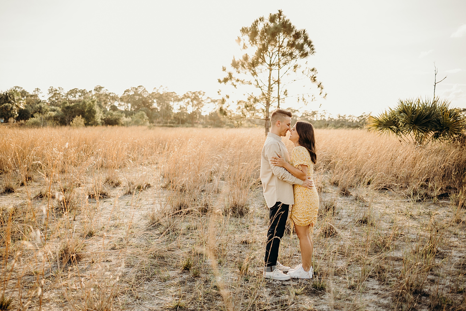 Couple touching noses on tall grass field Royal Palm Nature Preserve Engagement Photography captured by South Florida Engagement Photographer Maggie Alvarez Photography