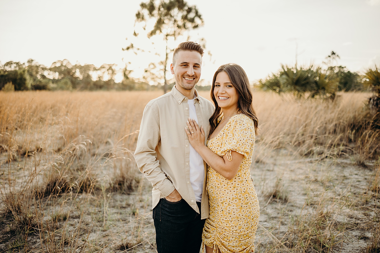 Couple posing with lady putting hand on man's chest showing off engagement ring Royal Palm Nature Preserve Engagement Photography captured by South Florida Engagement Photographer Maggie Alvarez Photography