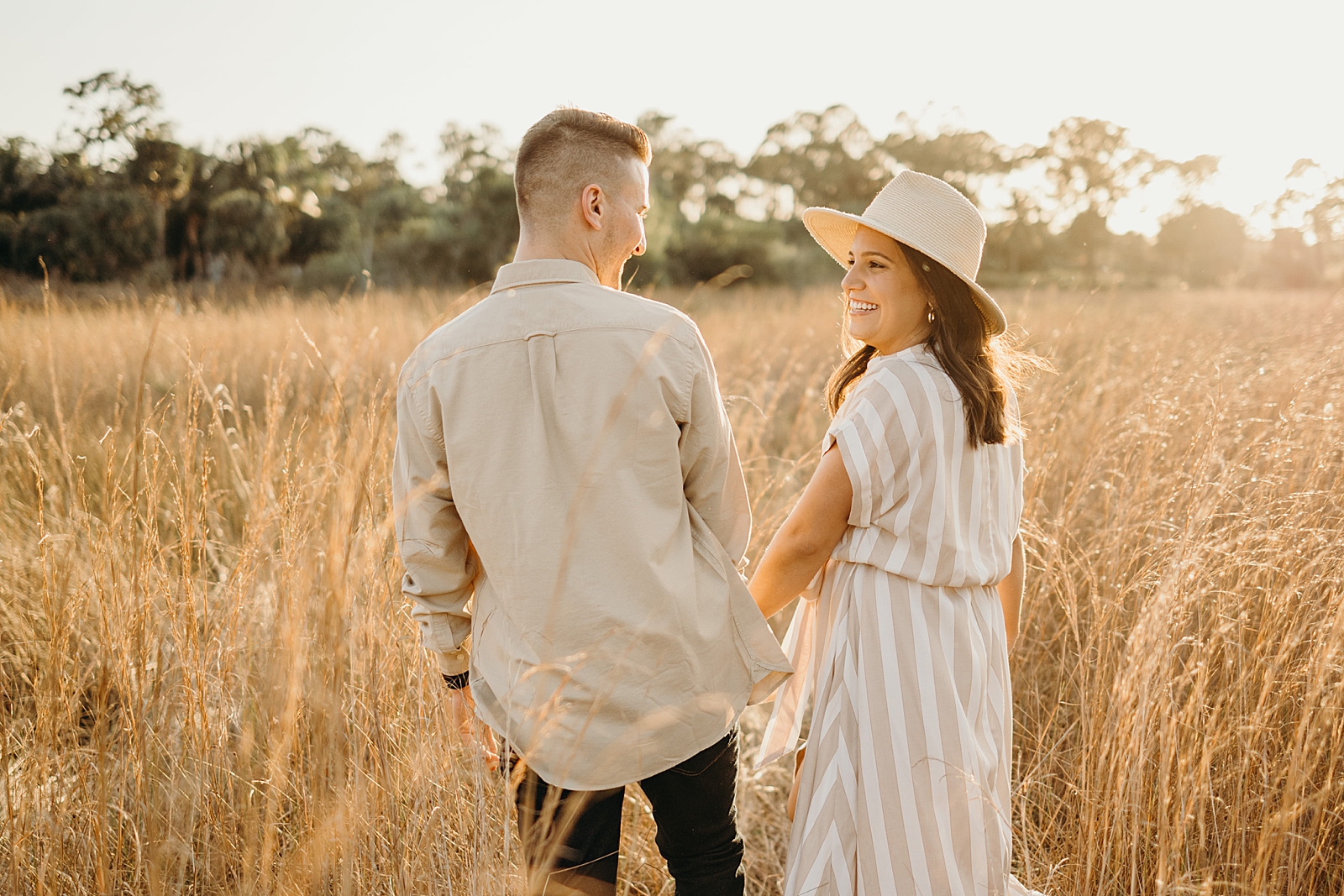 Couple with their back turned holding hands and smiling at each other Royal Palm Nature Preserve Engagement Photography captured by South Florida Engagement Photographer Maggie Alvarez Photography