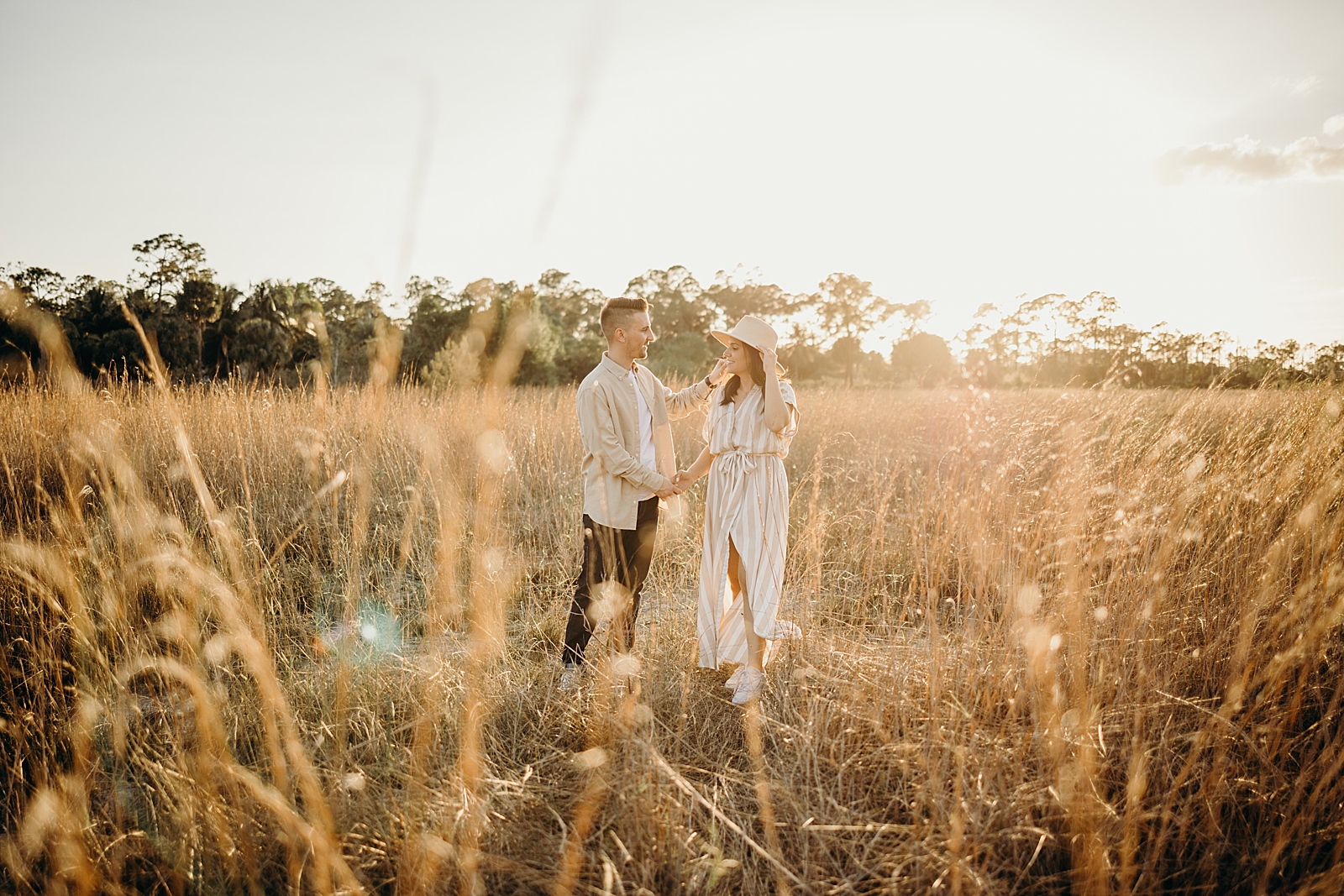 Candid photo of couple standing on tall grain field Royal Palm Nature Preserve Engagement Photography captured by South Florida Engagement Photographer Maggie Alvarez Photography