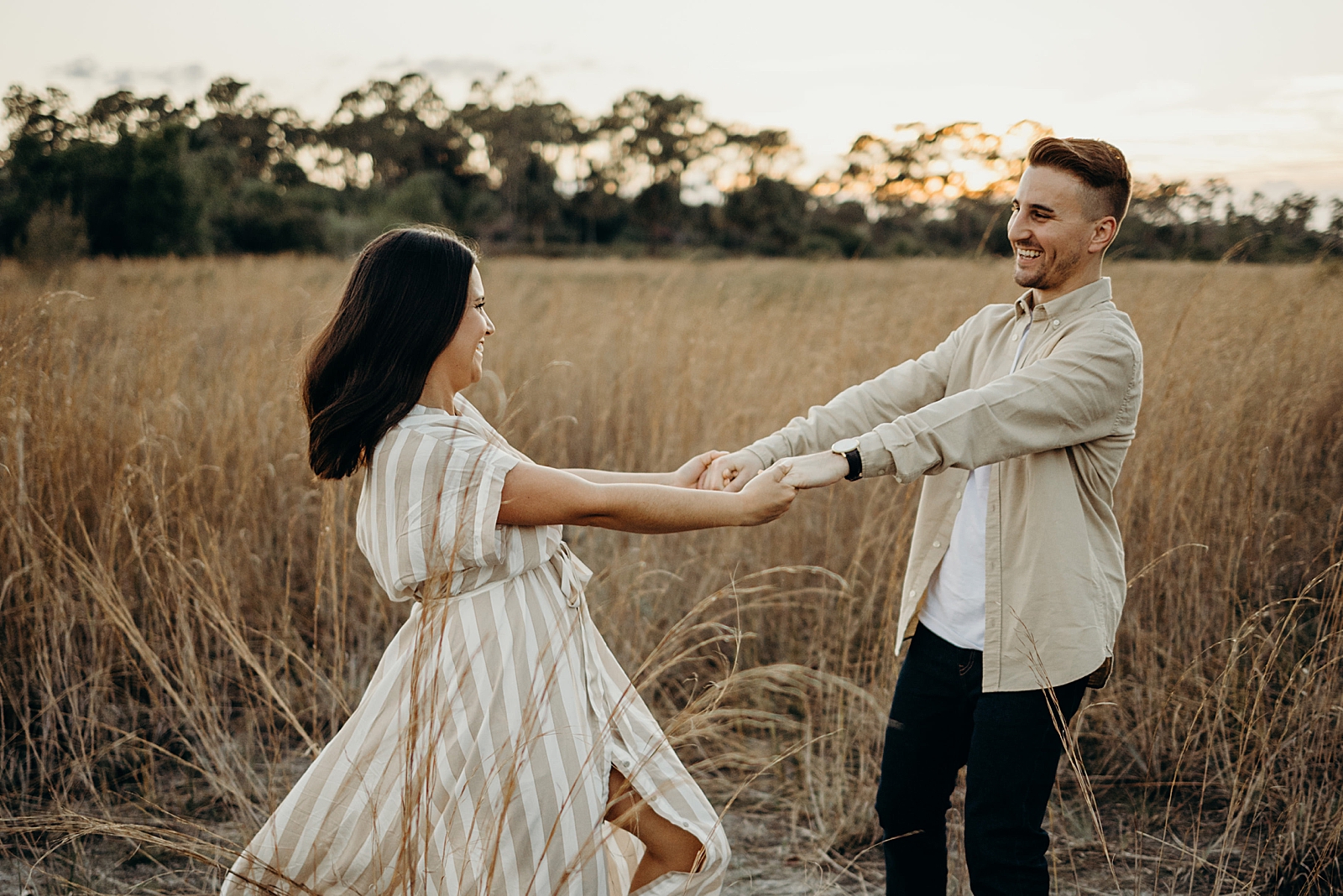 Couple holding hands and spinning in the field Royal Palm Nature Preserve Engagement Photography captured by South Florida Engagement Photographer Maggie Alvarez Photography