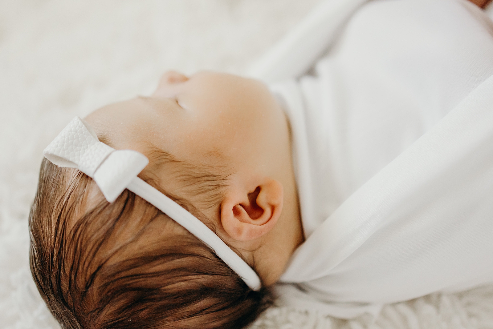 Closeup of sleeping baby's head with white bow head band South Florida Newborn Photography Photography captured by South Florida Family Photographer Maggie Alvarez Photography