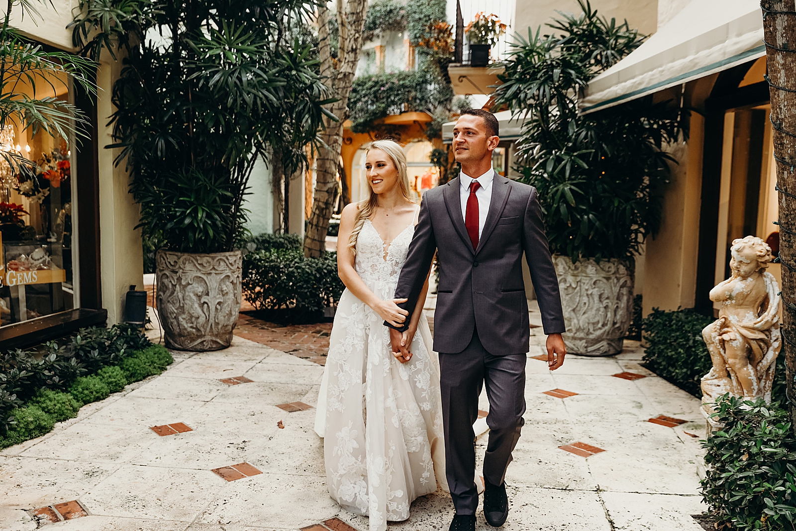Couple holding hands and walking through courtyard Worth Avenue Bridal Photography captured by South Florida Engagement Photographer Maggie Alvarez Photography