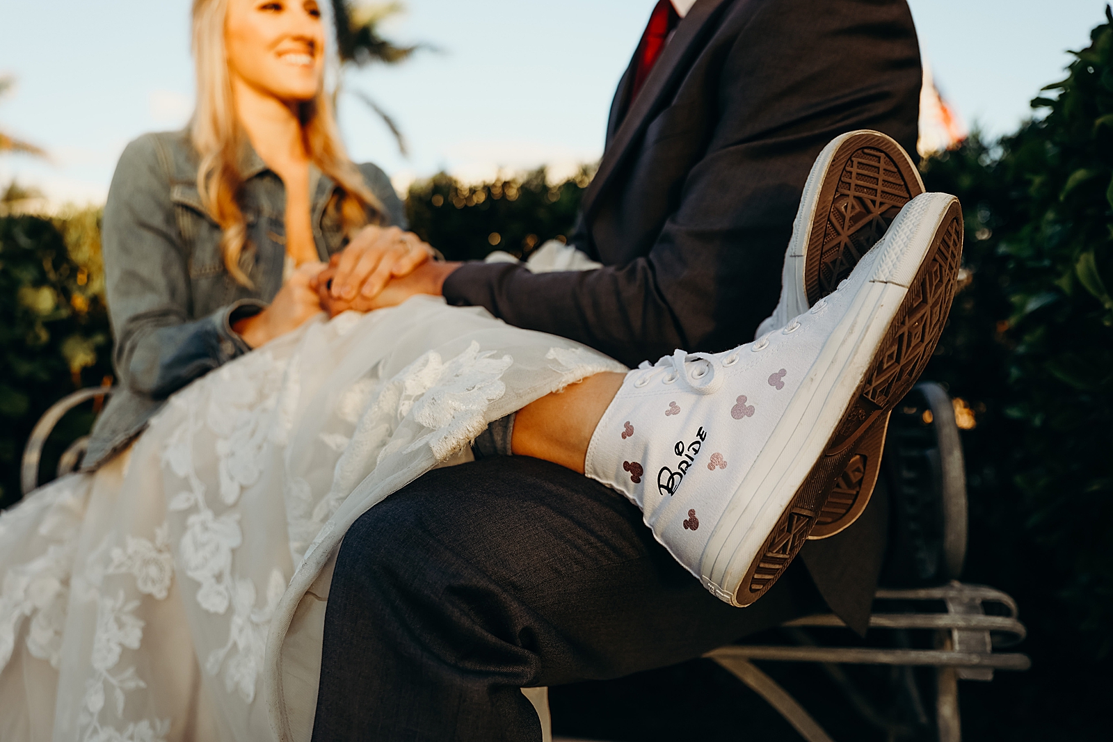Woman putting her legs on man's lap with Disney themed Bride shoes with mickey mouse on them Worth Avenue Bridal Photography captured by South Florida Engagement Photographer Maggie Alvarez Photography