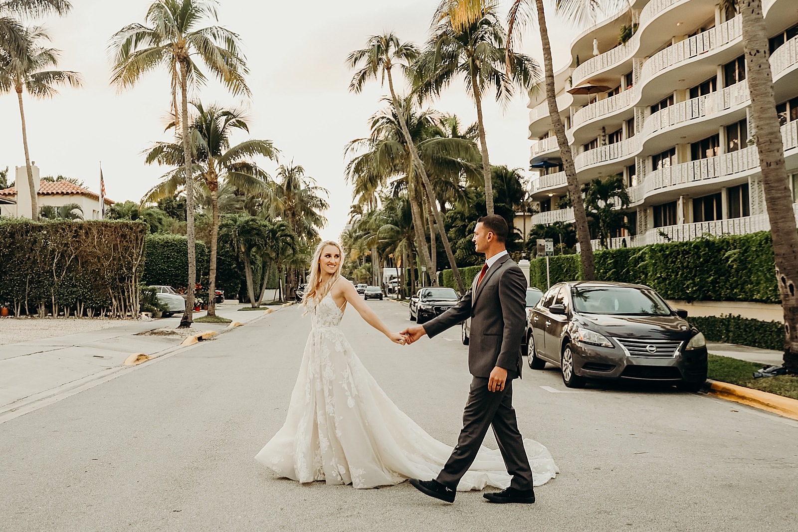 Lady holding man's hand leading man across the street Worth Avenue Bridal Photography captured by South Florida Engagement Photographer Maggie Alvarez Photography