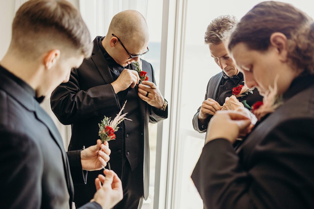 Groomsmen getting ready putting on boutonnieres 