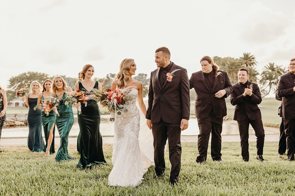 Bride and Groom holding hands and walking together with wedding party behind them