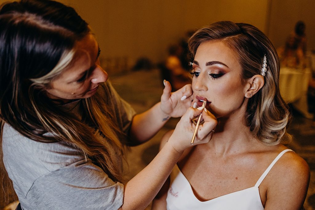 Bride getting makeup done by makeup artist